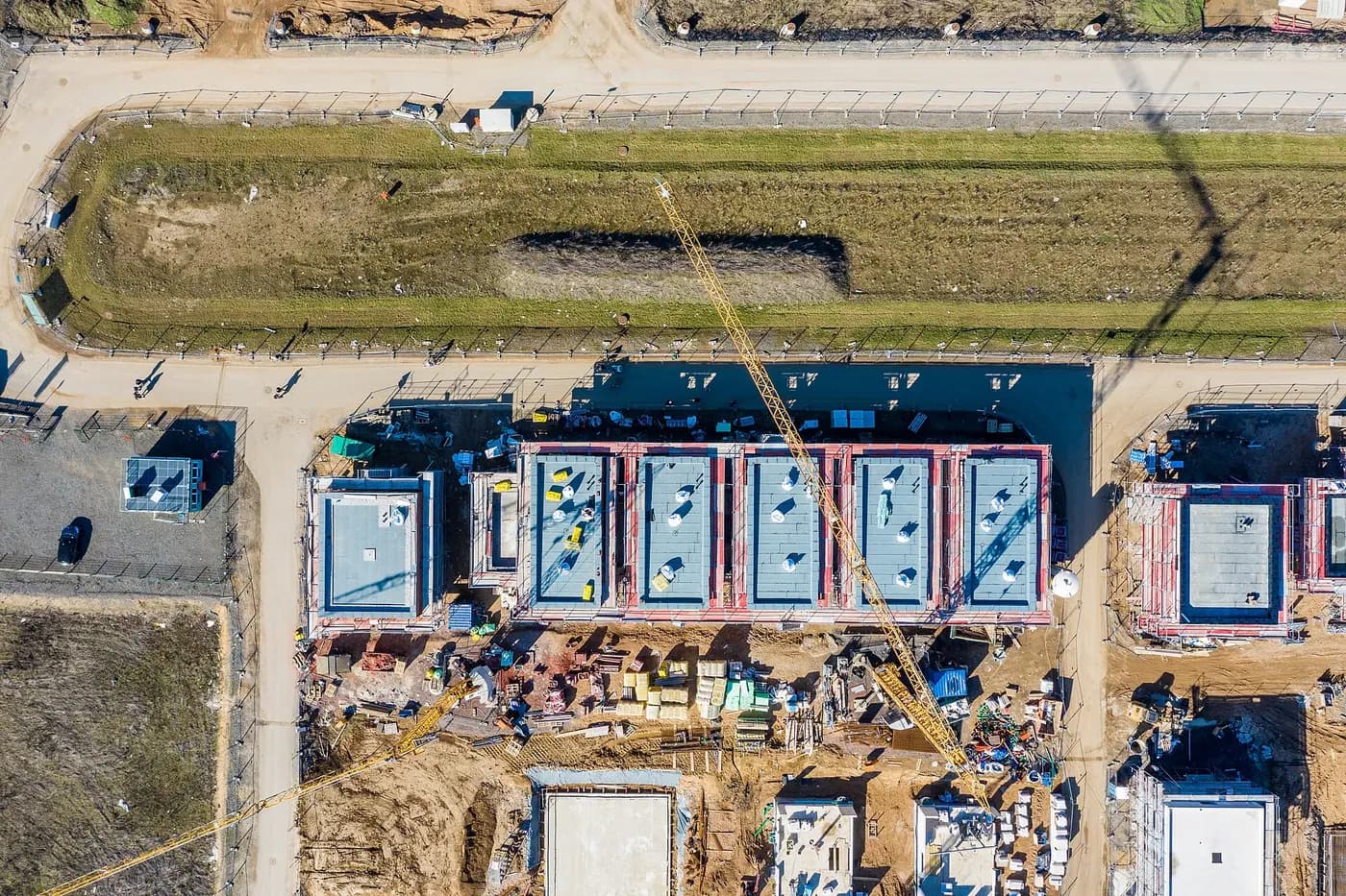 Straight-down drone photo of a townhouse row under construction beside a grass berm